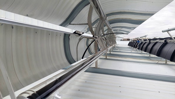 Colector solar de tubos de vacío con tubos de vidrio reflectantes y estructura metálica sobre cubierta industrial.