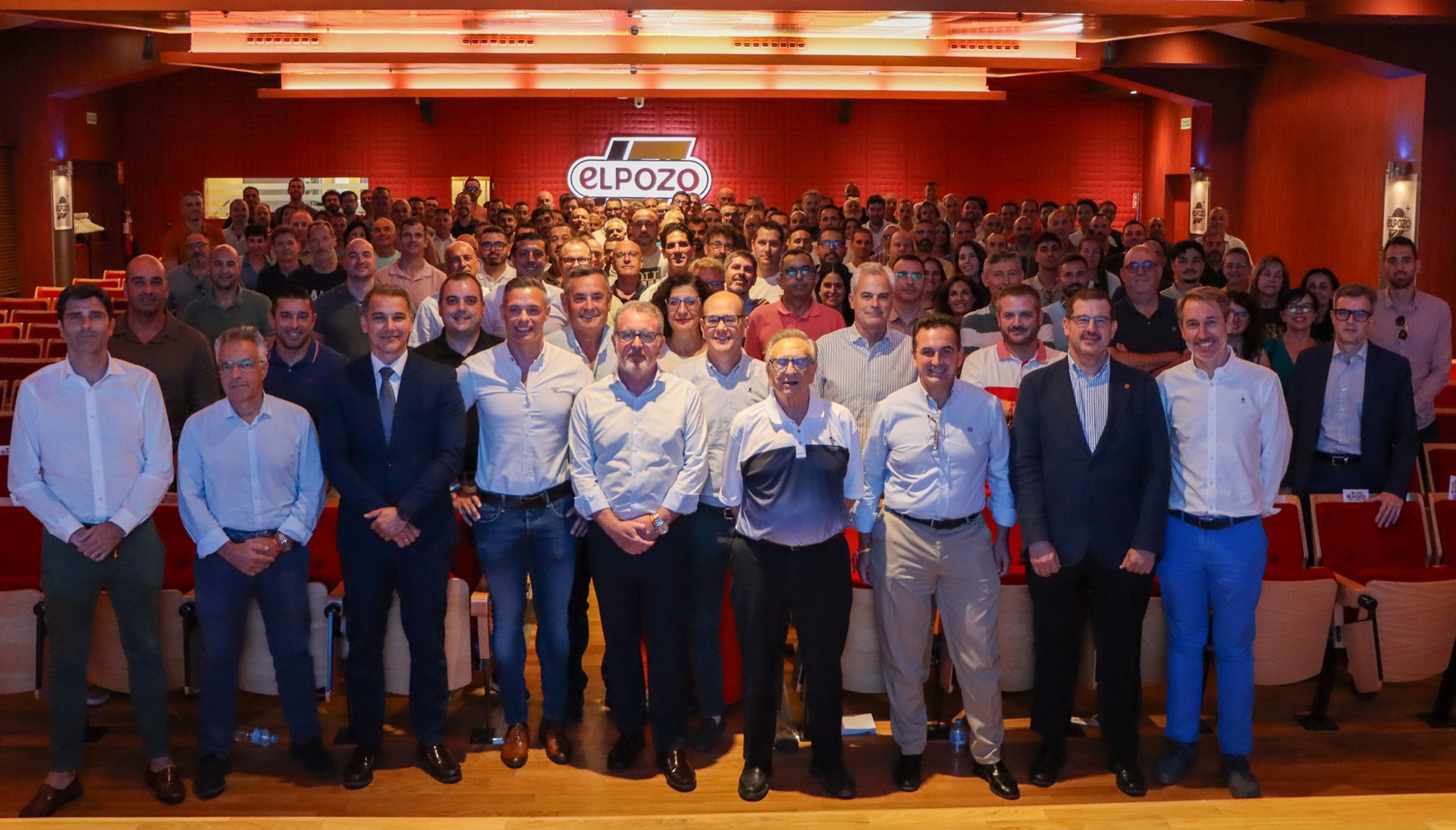 Grupo de empleados en un auditorio con el logotipo ELPOZO visible en la pared posterior.