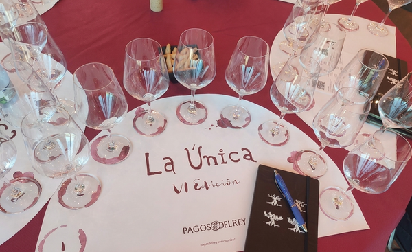Mesa de cata con copas de vino sobre mantel y cartel 'La Única VI edición' de Pagos del Rey.