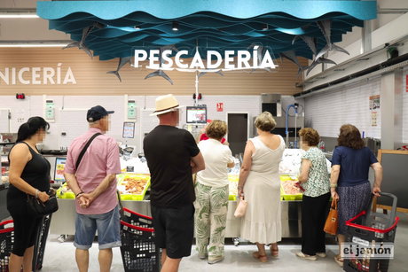 Mostrador de pescadería con varios clientes de espaldas junto a cestas y el rótulo PESCADERÍA; logotipo el jamón en un carro.