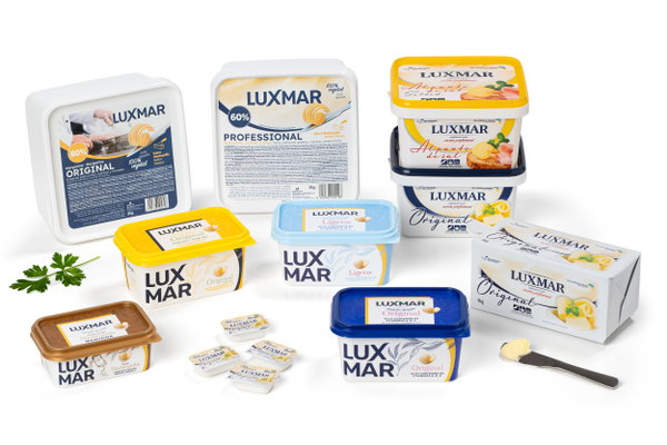 Envases de mantequilla y margarina LUXMAR en distintos formatos sobre fondo blanco, con cucharilla y porciones.