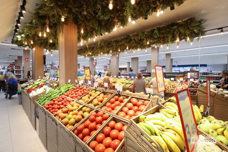 Lineal de frutas y verduras en supermercado Supermercados El Jamón con tomates, plátanos, pimientos y techo vegetal iluminado