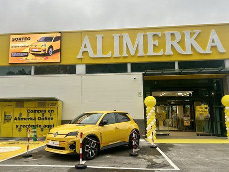 Coche promocional amarillo aparcado frente a la fachada de ALIMERKA con columnas de globos y señalética de recogida online.