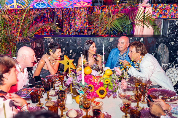 Mesa de gala con invitados conversando en la XVII Gala Starlite Occident, centro floral con frutas, copas y cartel con número