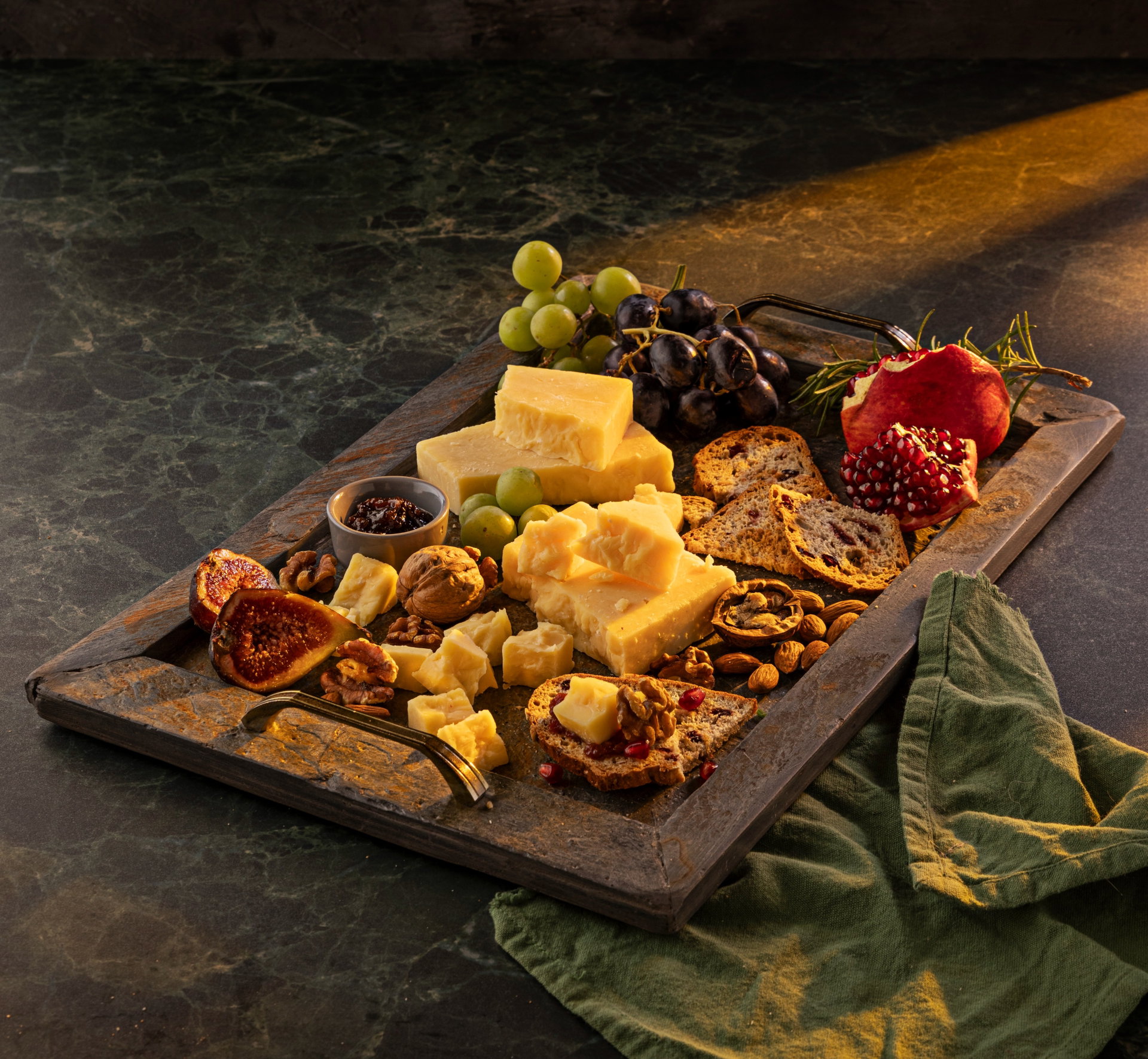 Tabla de quesos curados con uvas verdes y negras, granada partida, higos, nueces y tostas.