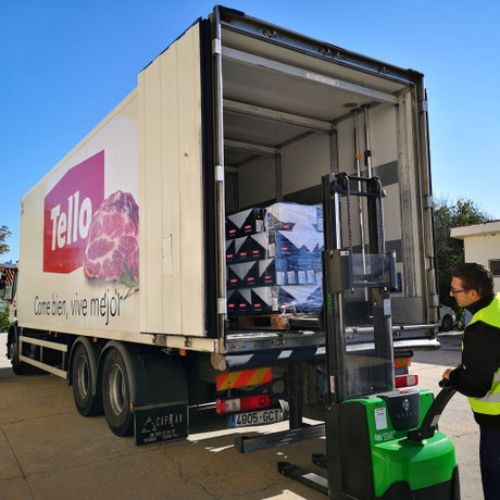 Camión frigorífico Tello con puerta abierta, pallet de cajas en el interior y transpaleta eléctrica con operario con chaleco