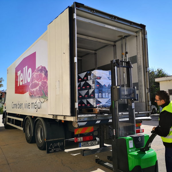 Camión frigorífico Tello con puerta abierta, pallet de cajas en el interior y transpaleta eléctrica con operario con chaleco