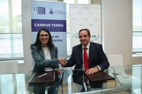 Mujer y hombre estrechando la mano durante la firma de un acuerdo frente a los rollups con los logos USC, CAMPUS TERRA y LACT