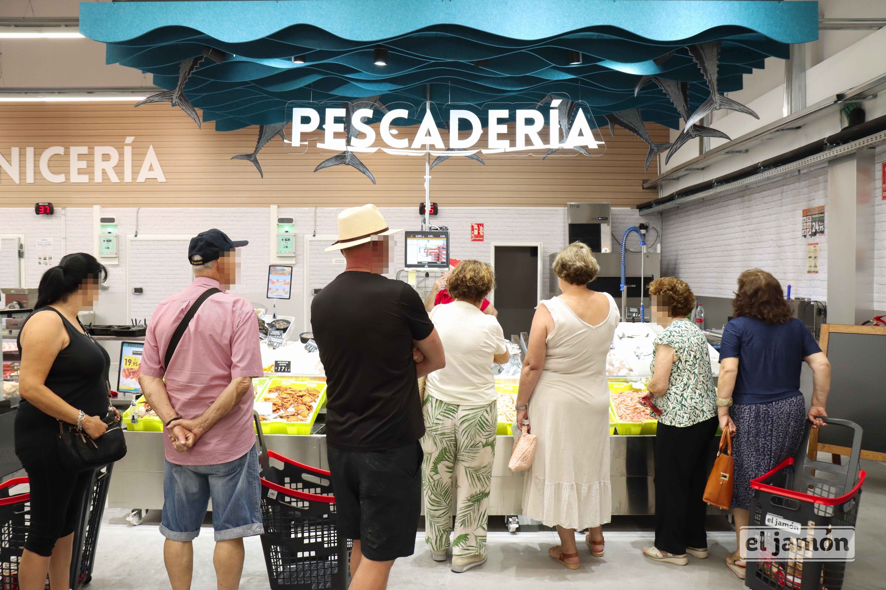 Mostrador de pescadería con varios clientes de espaldas junto a cestas y el rótulo PESCADERÍA; logotipo el jamón en un carro.